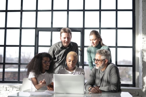 People Sitting at Table Near Window Using Laptop